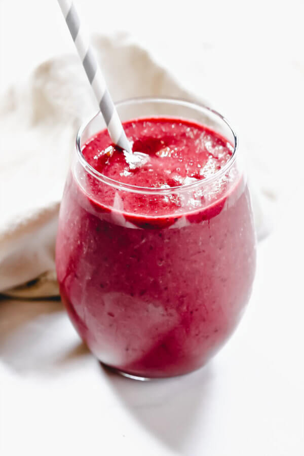Close up image of a glass filled with The BEST Vegan Cherry and Banana Smoothie with a grey and white straw inserted in the glass