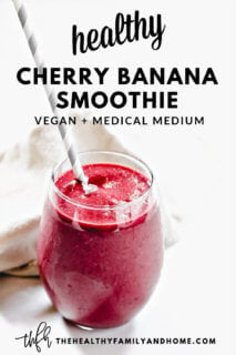 A glass filled with The BEST Vegan Cherry Banana Smoothie with a grey and white straw inserted on a white background with text overlay
