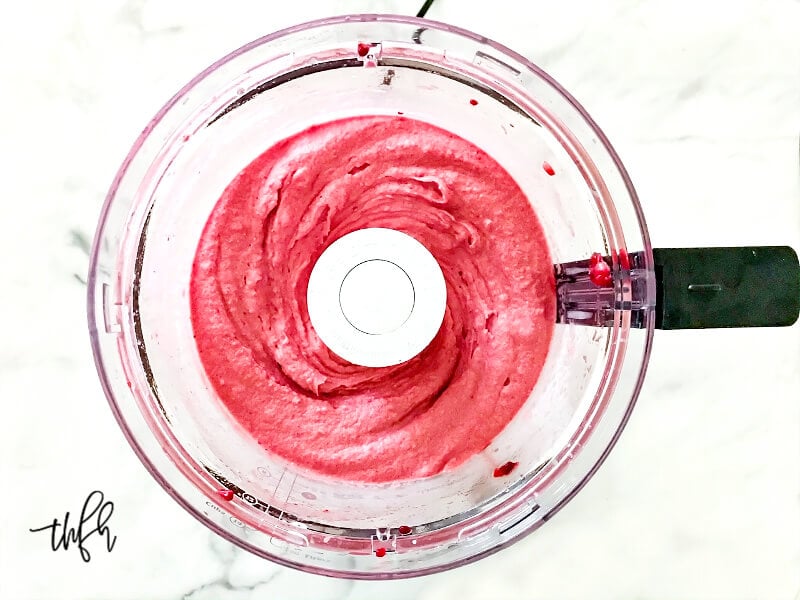 Overhead image of smooth and creamy raspberry and banana "nice" cream" in a food processor fully blended