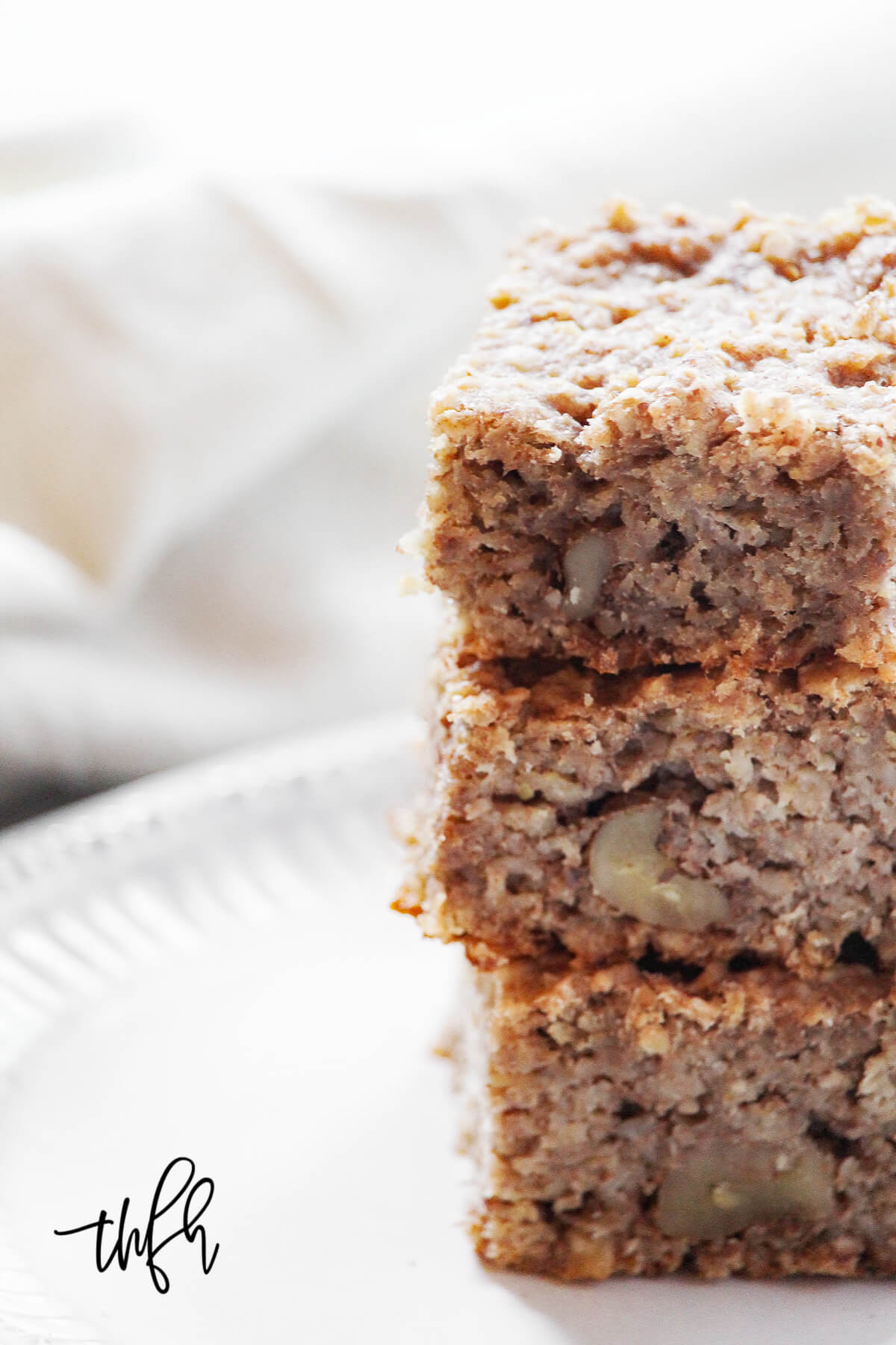 Close-up vertical image of a stack of three baked oatmeal breakfast bars on a white plate