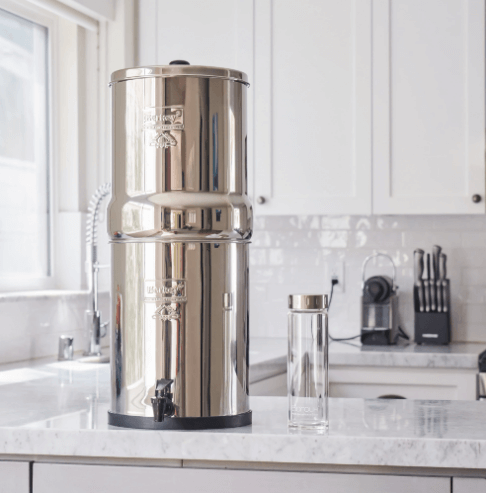 A Berkey water purification unit sitting on top of a white countertop in a clean bright kitchen