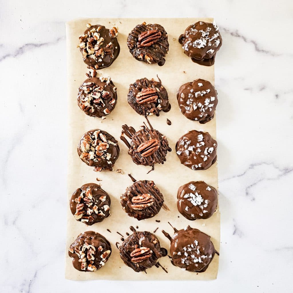 Overhead image of Gluten-Free Vegan Chocolate Turtles on parchment paper on a white marble surface