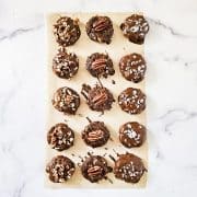Overhead image of Gluten-Free Vegan Chocolate Turtles on parchment paper on a white marble surface