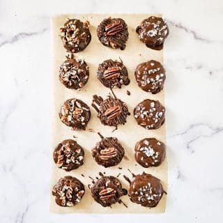 Overhead image of Gluten-Free Vegan Chocolate Turtles on parchment paper on a white marble surface