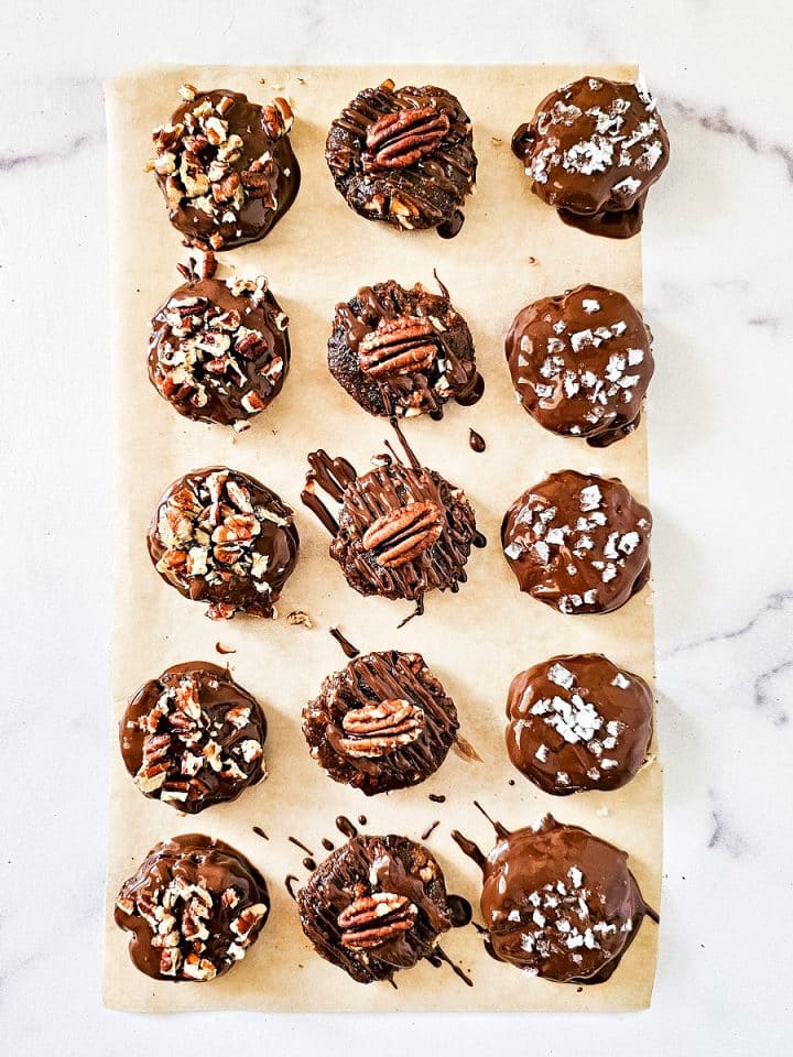 Overhead image of Gluten-Free Vegan Chocolate Turtles on parchment paper on a white marble surface