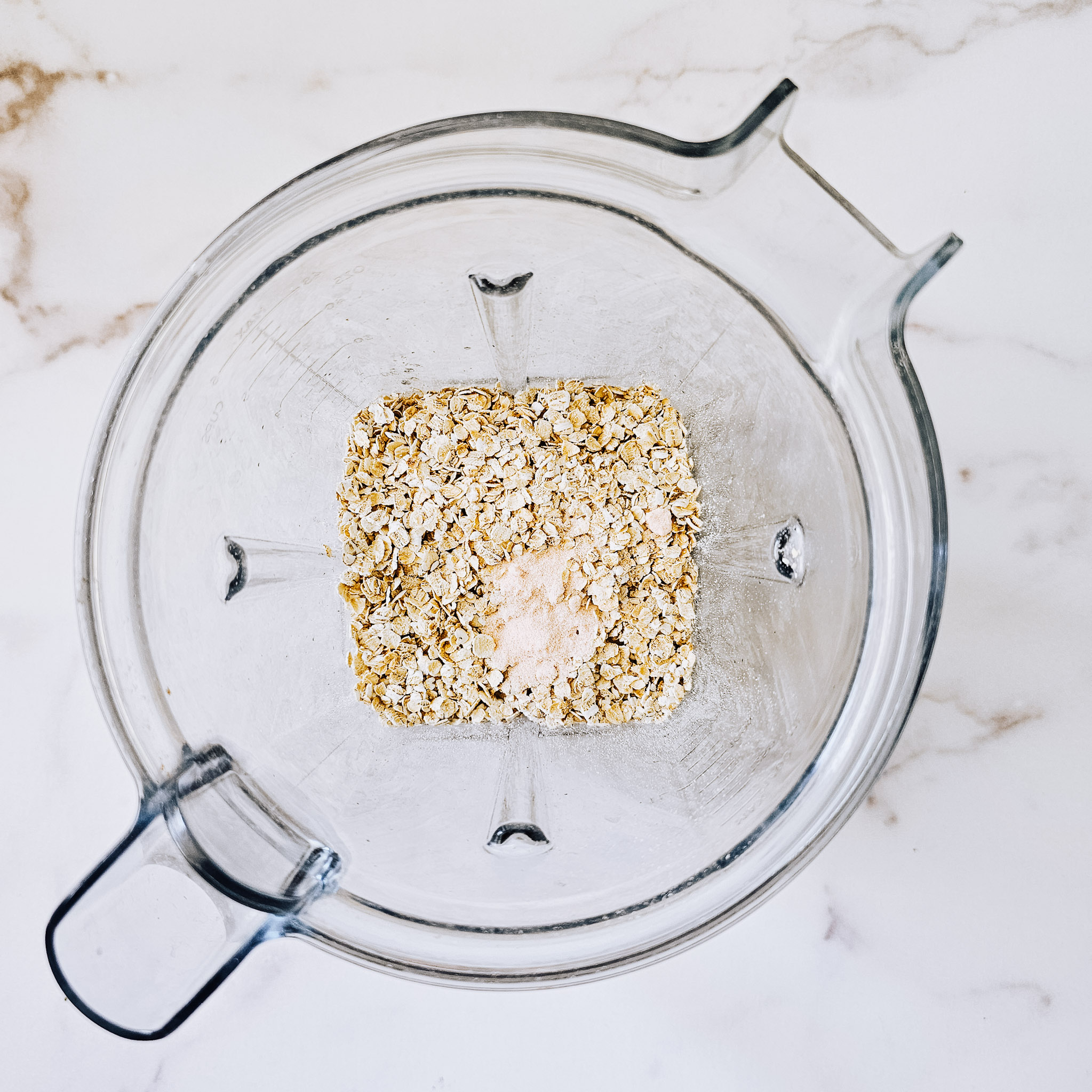Overhead image of ingredients needed to make gluten-free vegan oat tortillas added into a Vitamix blender on a white marble surface.