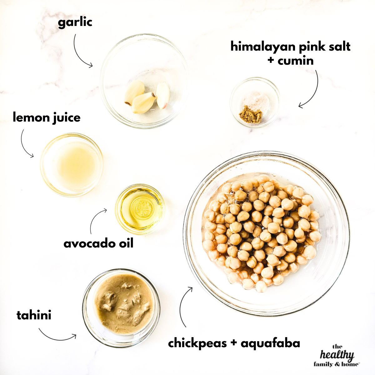 Overhead image of labeled ingredients needed to make gluten-free vegan creamy musabaha in glass bowls on a white marble surface.